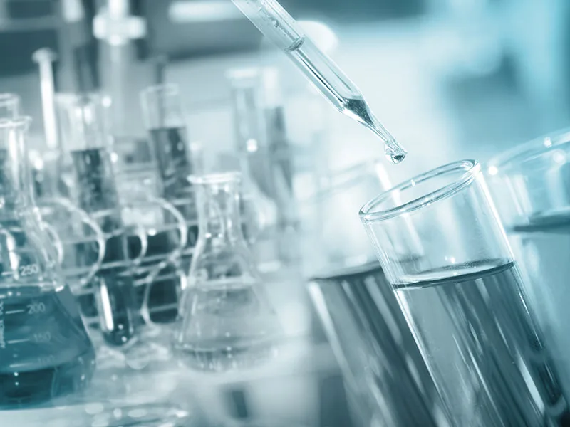 Pipette dropping liquid into a test tube in a laboratory